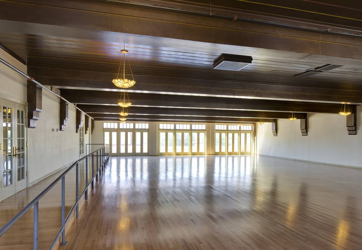 The historic grand ballroom with restored wood floors, beamed ceiling, and chandeliers