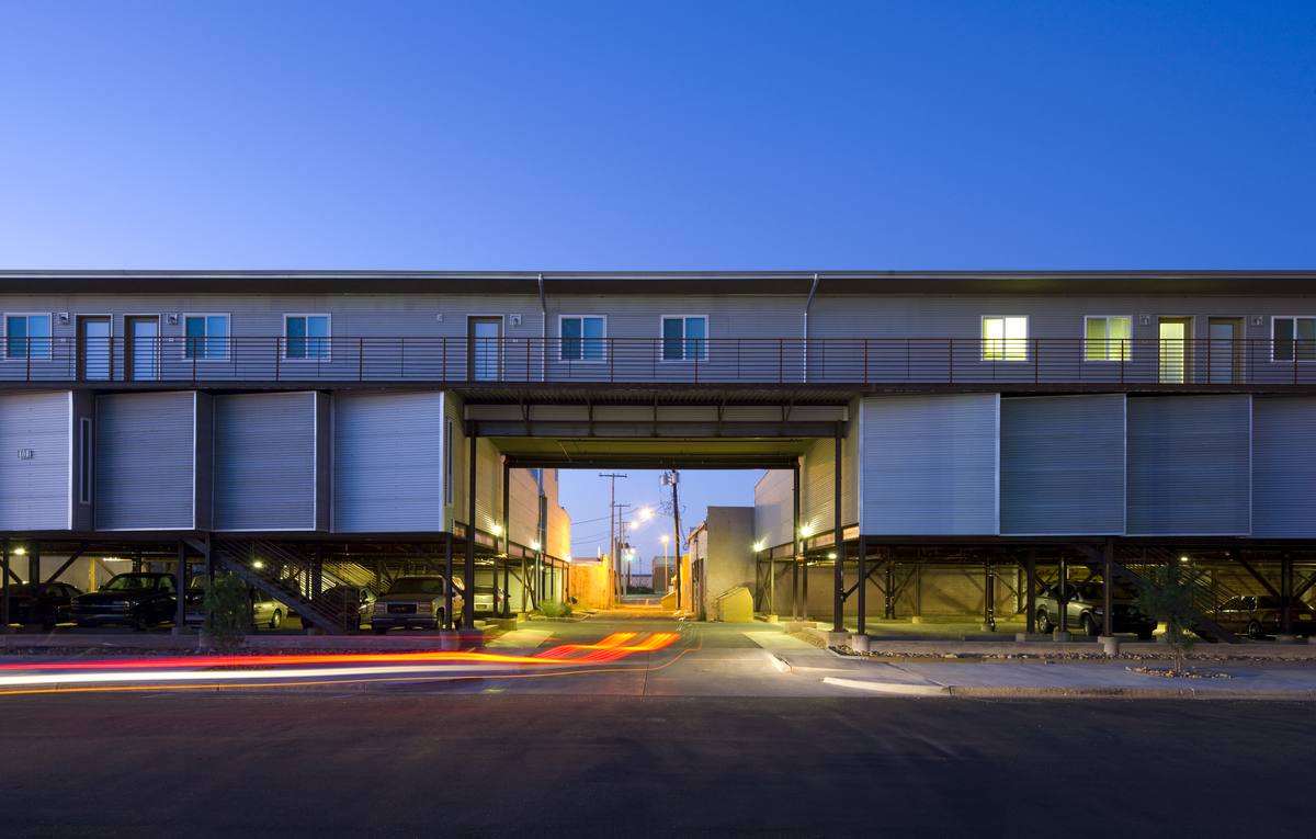 The new building at dusk with homes elevated over covered parking