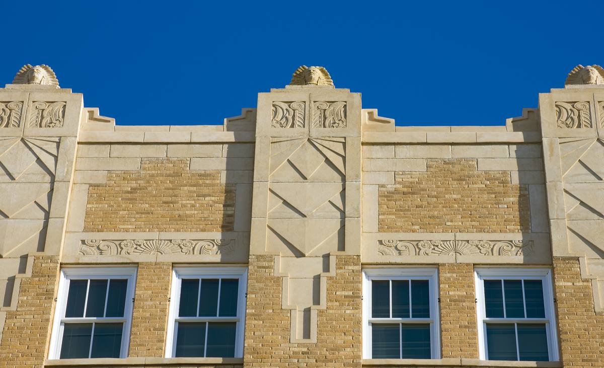Art deco stone figures along the parapet against a blue New Mexico sky
