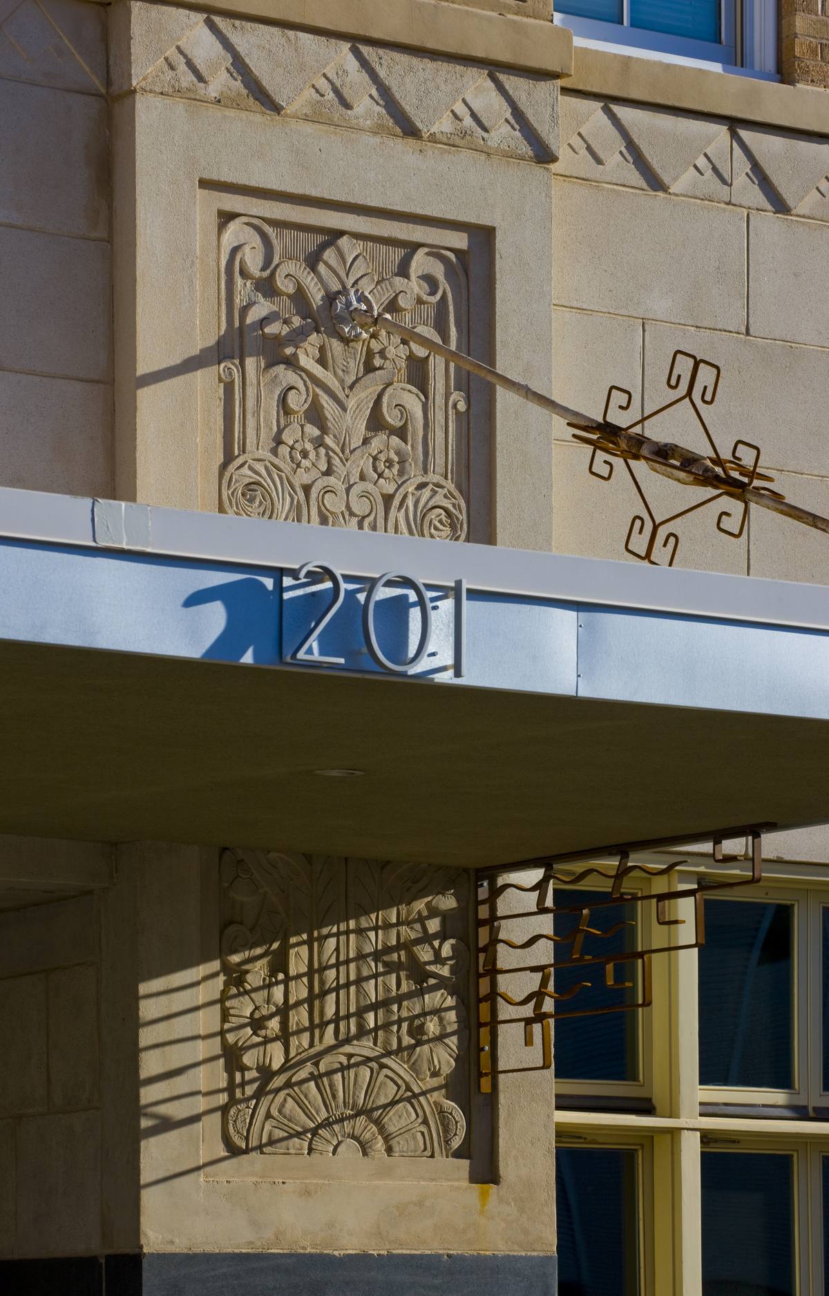 Carved art deco relief and ironwork above the entrance canopy