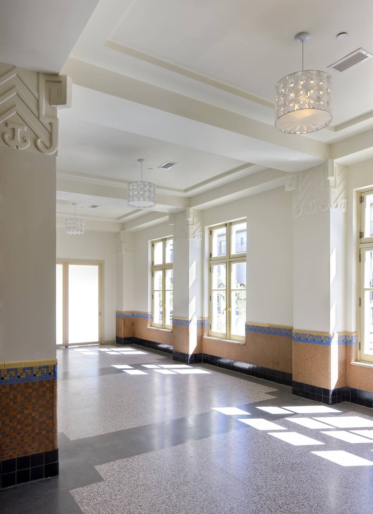 Sunlight across the restored lobby with art deco columns and tile wainscot